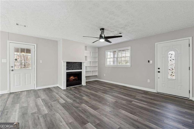 unfurnished living room featuring ceiling fan, dark hardwood / wood-style floors, built in features, and a textured ceiling