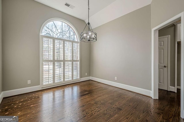 unfurnished dining area featuring dark hardwood / wood-style flooring, an inviting chandelier, and lofted ceiling