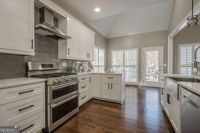 kitchen with white cabinetry, wall chimney exhaust hood, backsplash, lofted ceiling, and appliances with stainless steel finishes