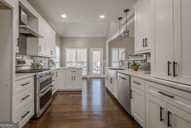 kitchen with tasteful backsplash, stainless steel appliances, white cabinetry, hanging light fixtures, and lofted ceiling