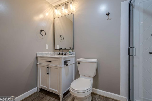 bathroom with hardwood / wood-style floors, vanity, toilet, and walk in shower