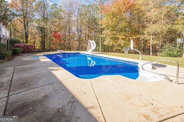 view of swimming pool featuring a patio, a diving board, and a water slide