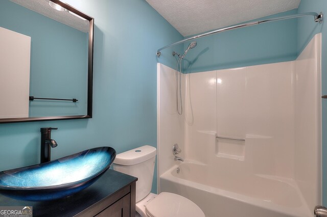 full bathroom featuring vanity, shower / bathtub combination, toilet, and a textured ceiling