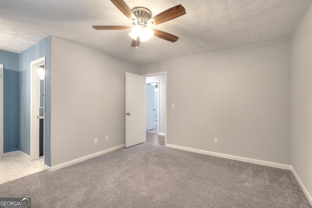 carpeted spare room featuring ceiling fan and a textured ceiling