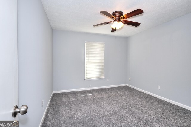 spare room with dark colored carpet, ceiling fan, and a textured ceiling