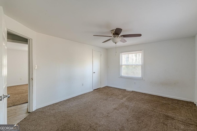 empty room featuring ceiling fan and light colored carpet