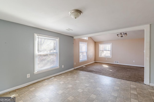 carpeted spare room with an inviting chandelier and vaulted ceiling