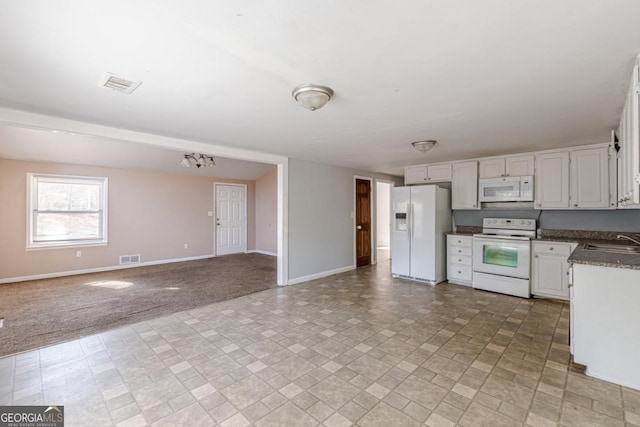 kitchen with sink, an inviting chandelier, light colored carpet, white appliances, and white cabinets