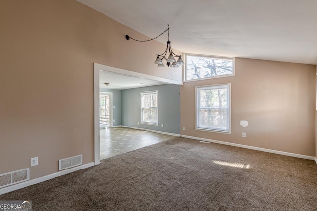 carpeted empty room featuring a notable chandelier and high vaulted ceiling