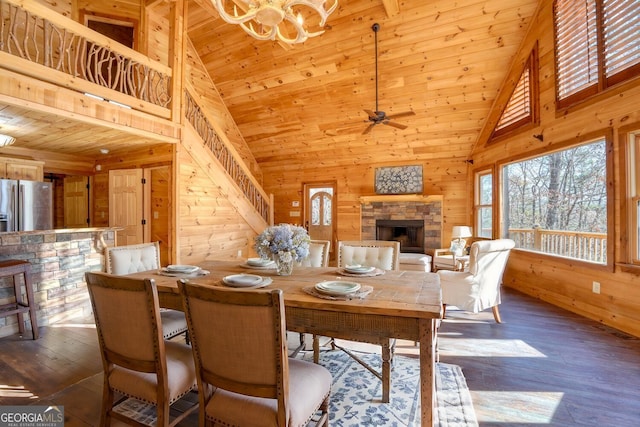 dining space with ceiling fan with notable chandelier, wood ceiling, dark wood-type flooring, and high vaulted ceiling