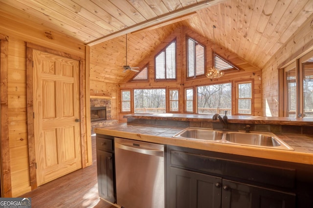 kitchen featuring tile countertops, stainless steel dishwasher, wooden walls, and wood ceiling