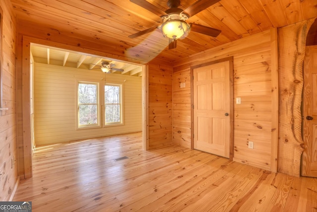 empty room featuring wood walls, light wood-type flooring, and wooden ceiling