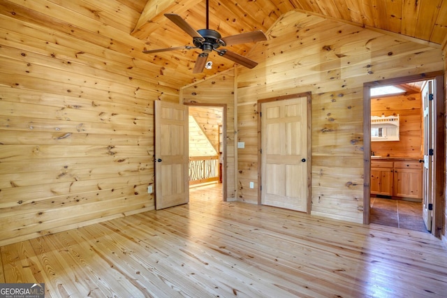 unfurnished bedroom featuring light hardwood / wood-style floors, wooden ceiling, wooden walls, and vaulted ceiling