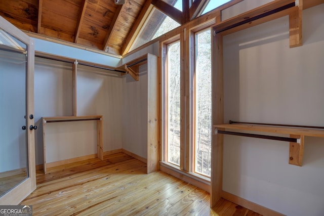 spacious closet with lofted ceiling with beams and light hardwood / wood-style flooring