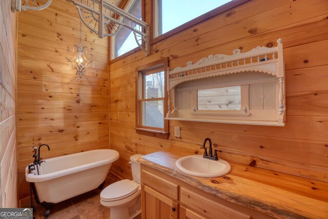 bathroom with vanity, tile patterned flooring, toilet, a tub, and wood walls