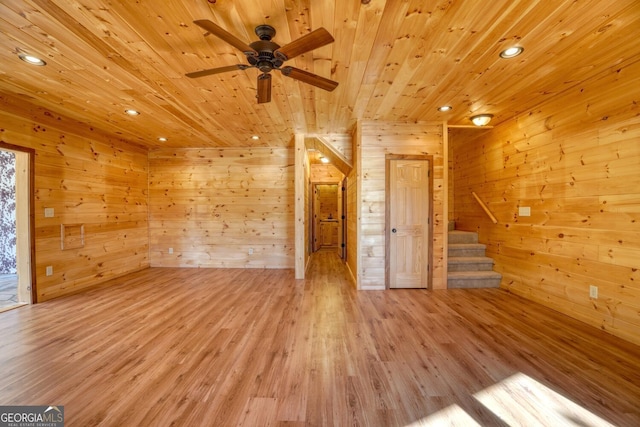 unfurnished living room featuring light wood-type flooring, ceiling fan, wooden walls, and wood ceiling