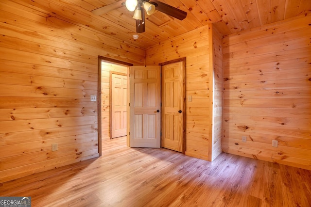 unfurnished bedroom featuring ceiling fan, light hardwood / wood-style flooring, wood ceiling, and wooden walls