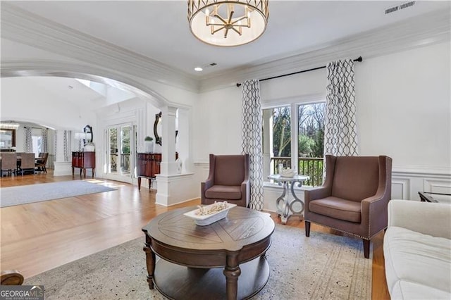 living area with light hardwood / wood-style floors, ornamental molding, and an inviting chandelier