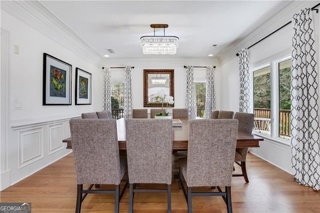 dining space featuring light wood-type flooring, an inviting chandelier, and crown molding