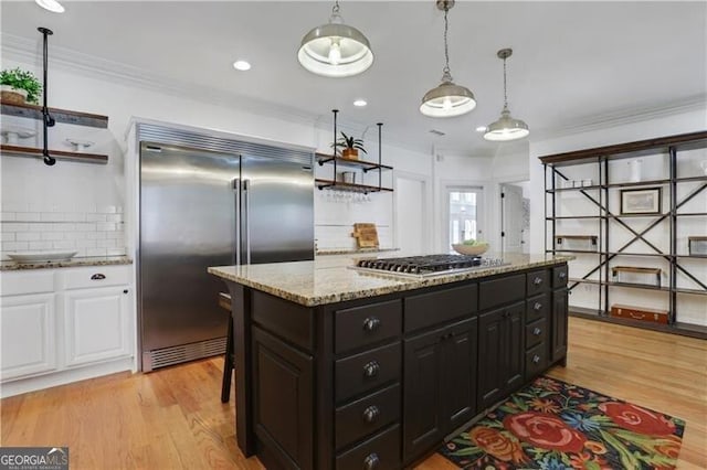 kitchen featuring pendant lighting, white cabinets, appliances with stainless steel finishes, decorative backsplash, and light wood-type flooring