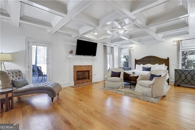 bedroom with beam ceiling, a fireplace, coffered ceiling, and light hardwood / wood-style floors