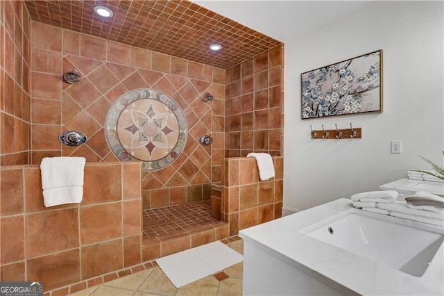 bathroom featuring tile patterned flooring, sink, and tiled shower