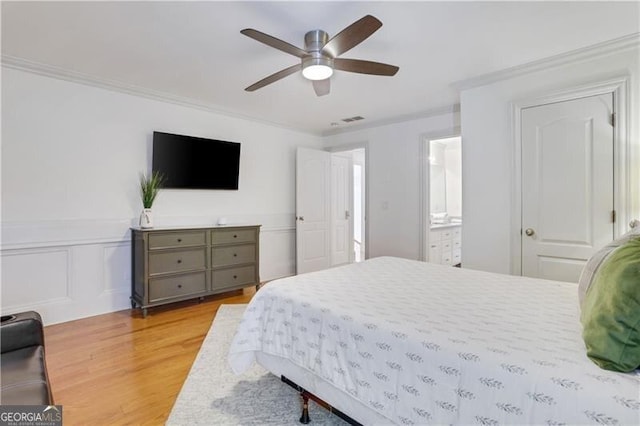 bedroom featuring ceiling fan, crown molding, ensuite bathroom, and light hardwood / wood-style flooring