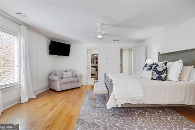 bedroom featuring ceiling fan, multiple windows, hardwood / wood-style flooring, and crown molding