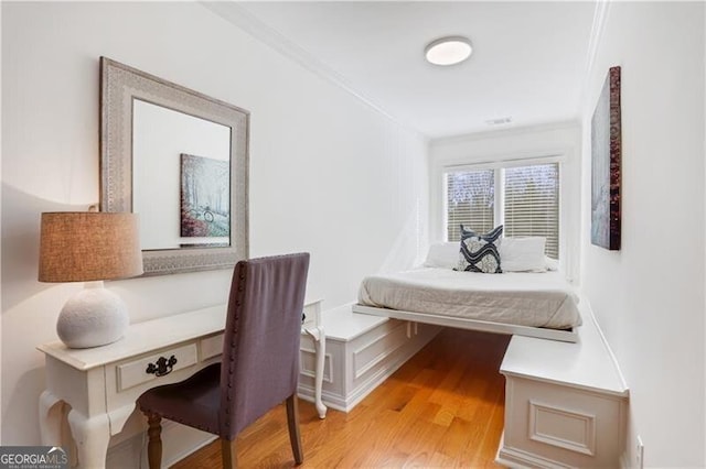 bedroom featuring ornamental molding and light wood-type flooring