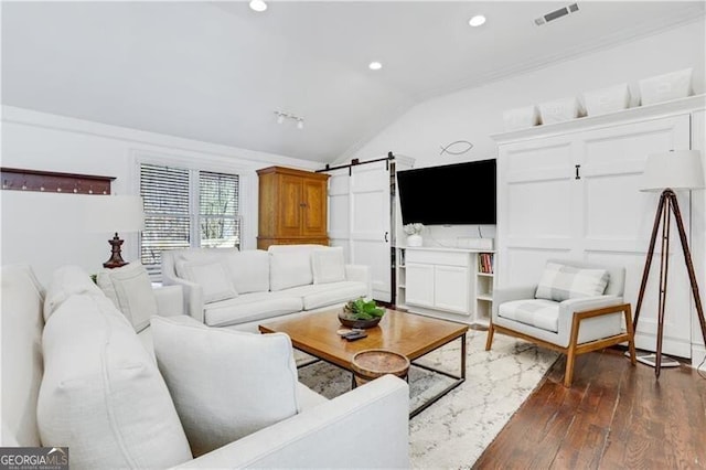 living room featuring ornamental molding, lofted ceiling, a barn door, and dark hardwood / wood-style floors