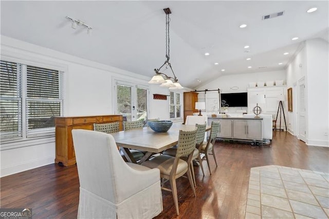 dining space with dark wood-type flooring, french doors, lofted ceiling, and a barn door