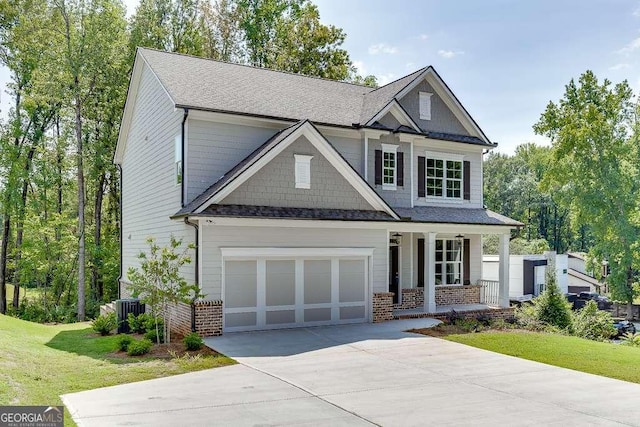 craftsman house with central AC, covered porch, a front yard, and a garage