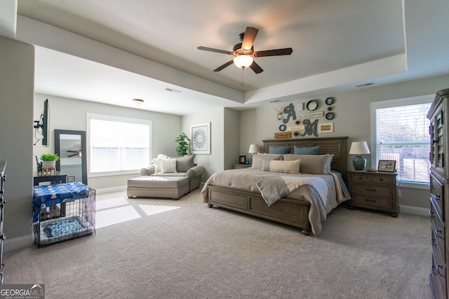 carpeted bedroom with ceiling fan and a tray ceiling