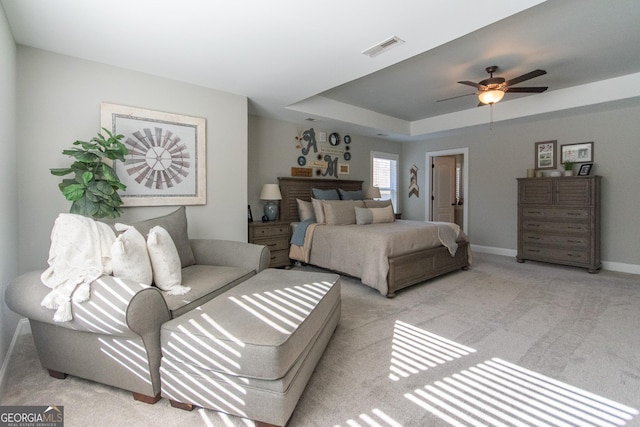 carpeted bedroom featuring a tray ceiling and ceiling fan