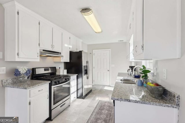 kitchen with white cabinets, stainless steel appliances, light stone counters, and sink