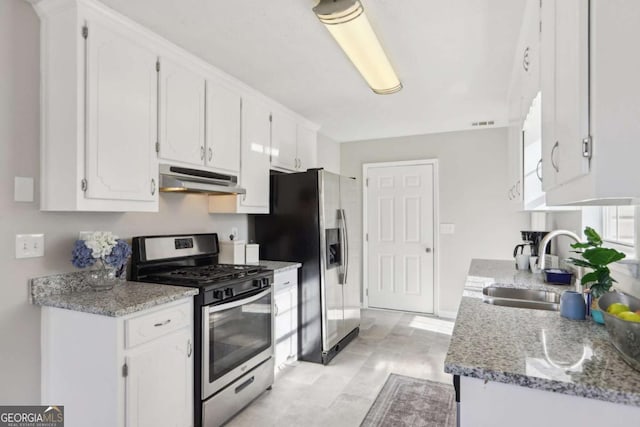 kitchen with light stone counters, stainless steel appliances, white cabinetry, and sink