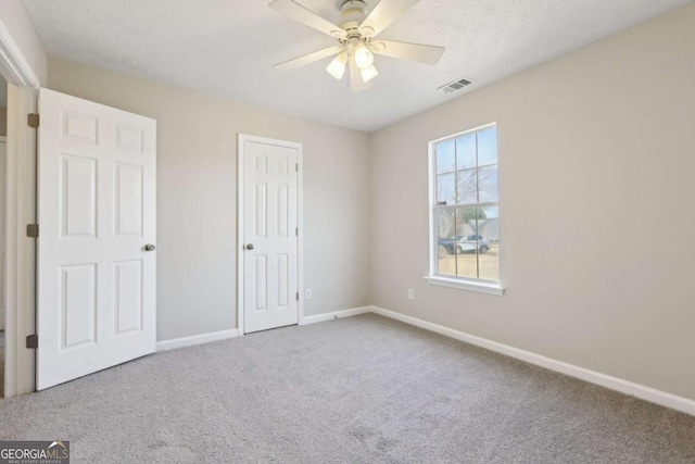 unfurnished bedroom featuring ceiling fan, carpet, and a textured ceiling