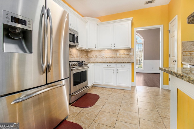 kitchen with white cabinetry, stainless steel appliances, light stone countertops, and tasteful backsplash