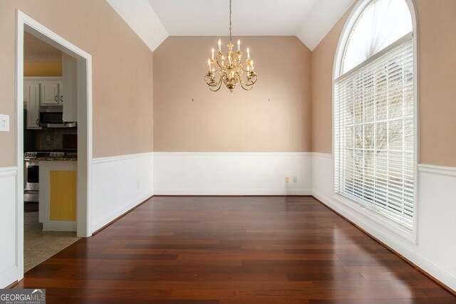 unfurnished room featuring lofted ceiling, dark wood-type flooring, and a notable chandelier