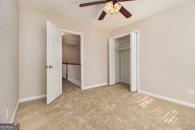 unfurnished bedroom featuring ceiling fan, light colored carpet, a closet, and a textured ceiling