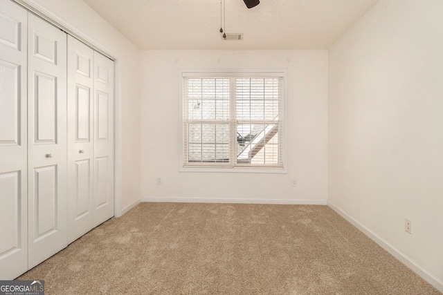 unfurnished bedroom featuring light colored carpet, a closet, and ceiling fan