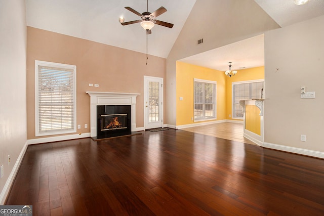 unfurnished living room with ceiling fan with notable chandelier, wood-type flooring, and high vaulted ceiling