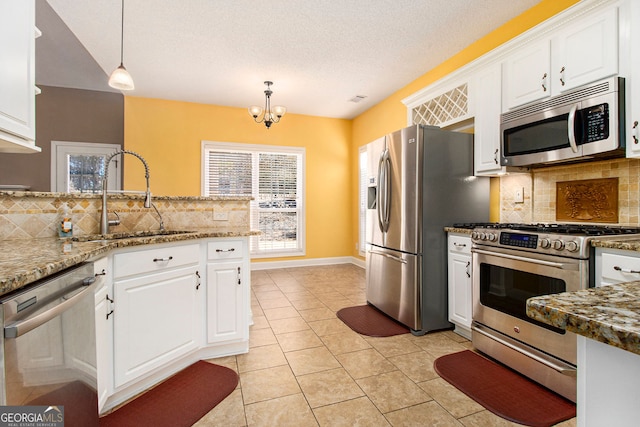 kitchen with appliances with stainless steel finishes, sink, pendant lighting, and white cabinets