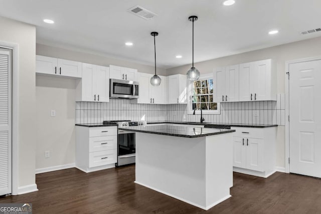 kitchen with a center island, hanging light fixtures, dark hardwood / wood-style floors, appliances with stainless steel finishes, and white cabinetry