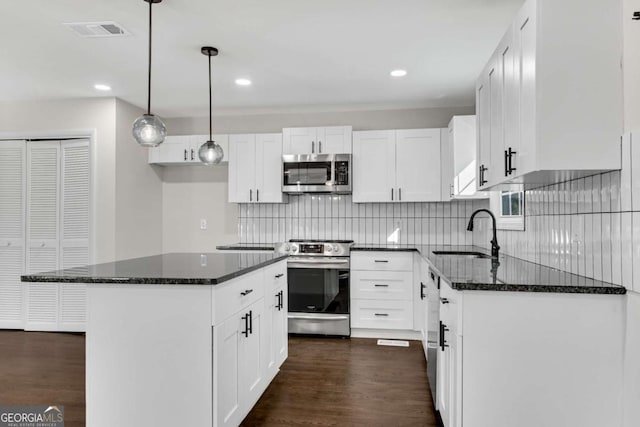 kitchen with white cabinets, sink, decorative light fixtures, a kitchen island, and stainless steel appliances