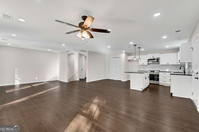 unfurnished living room featuring ceiling fan, dark wood-type flooring, and sink