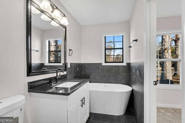 bathroom with vanity, tile patterned floors, toilet, tile walls, and a tub