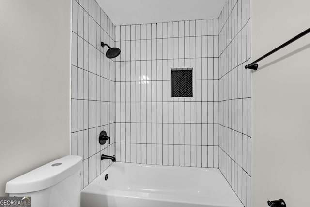 bathroom featuring tiled shower / bath combo and toilet