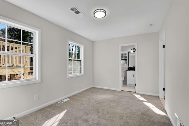 unfurnished bedroom featuring ensuite bathroom and light colored carpet