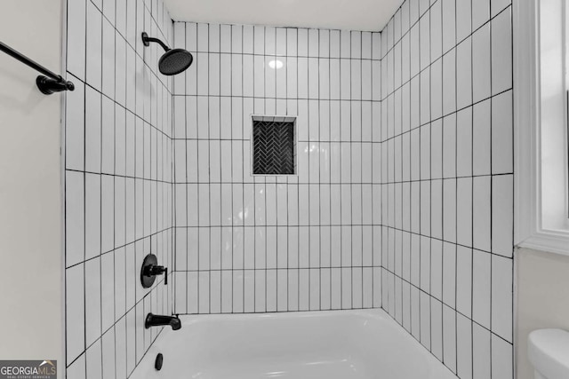 bathroom featuring toilet and tiled shower / bath